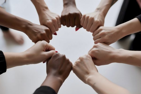 People of diverse skin tones fist bumping in a circle.
